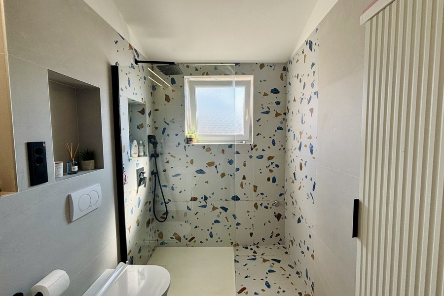 Modernt badrum med dusch i golvnivå och fönster