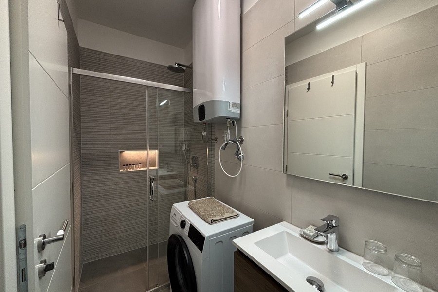 Modernt badrum med dusch och tvättmaskin