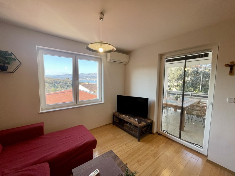 Vardagsrum med soffa, TV och tillgång till balkong med utsikt över havet