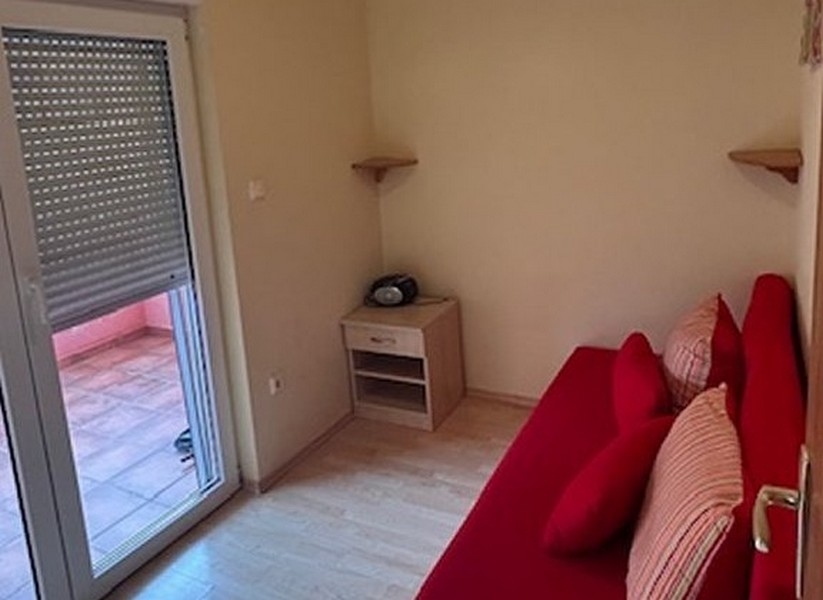 Sovrum med röd soffa och utgång till balkong