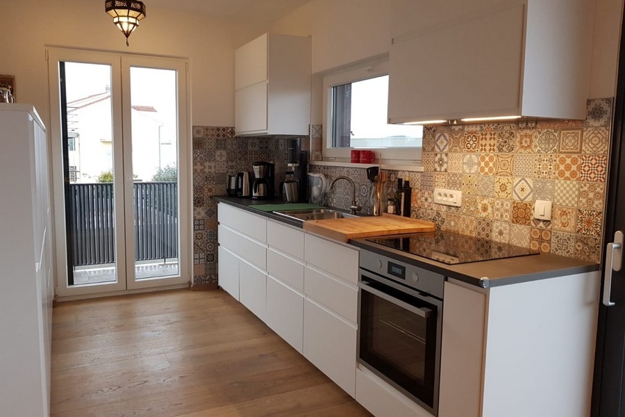 Modernt kök med inbyggda vitvaror och dekorativ kaklad stänk