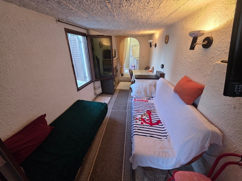 Smalt vardagsrum med sittplatser och fönster mot gatan