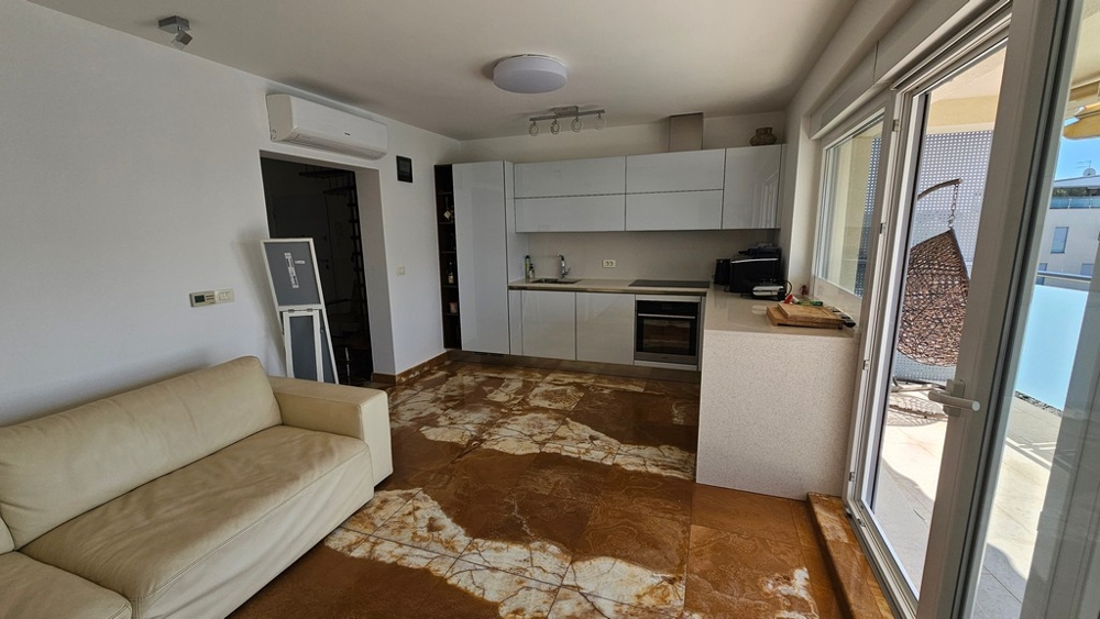 Öppet vardagsrum med modernt utrustat kök och tillgång till terrass