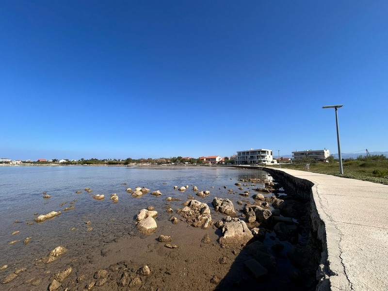 Kustlinje med strandpromenad och klart hav i Privlaka