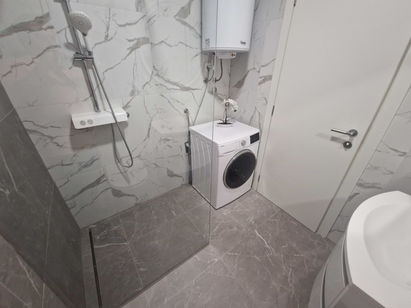 Badrum med dusch i golvnivå och tvättmaskin