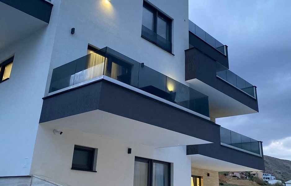Modernt bostadshus med balkonger och glasräcken i Pag