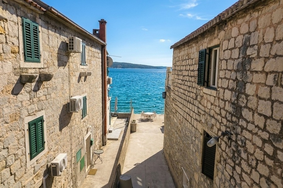 Utsikt över havet mellan naturstenshus i Kroatien