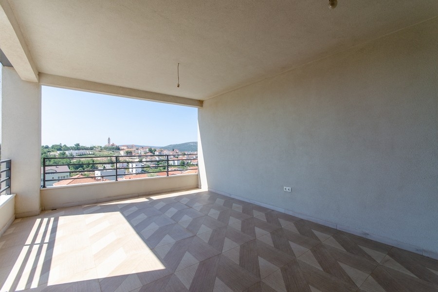 Solig loggia med fiskbensgolv och havsutsikt