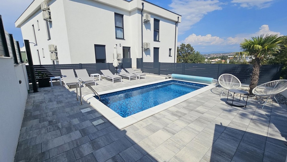 Ny byggnad med pool och solstolar i trädgården i Malinska på ön Krk