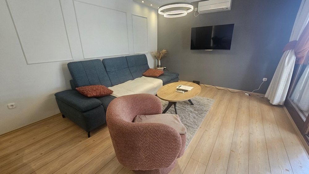 Vardagsrum med soffa och tv i renoverad lägenhet