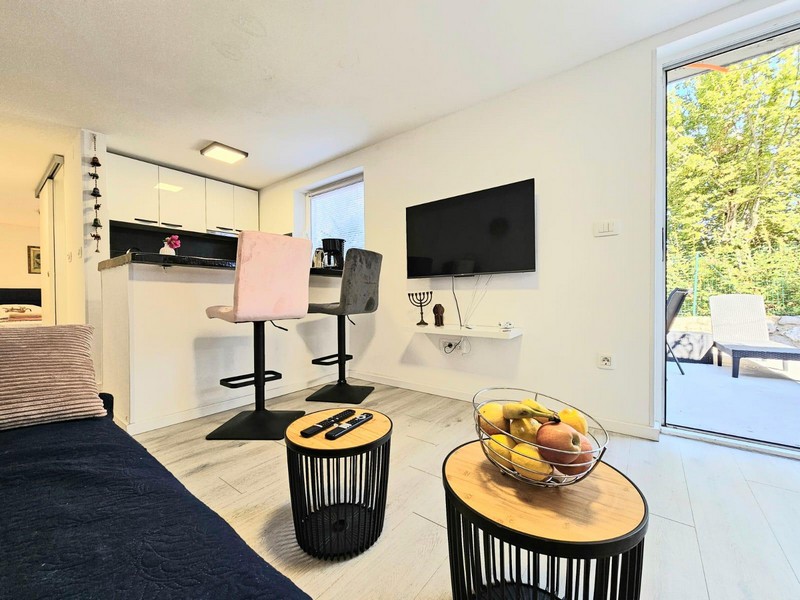 Möblerat vardagsrum med TV och barstolar i Njivice