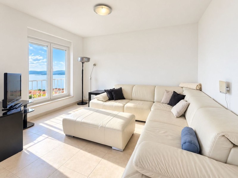 Vardagsrum med läderbäddsoffa och fönster mot havet