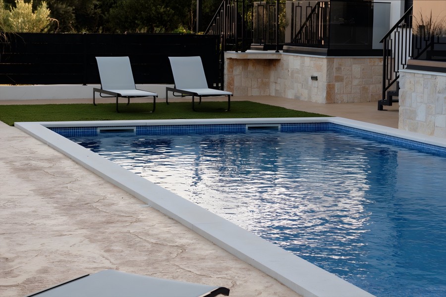 Swimmingpool med gräsmatta och solstolar