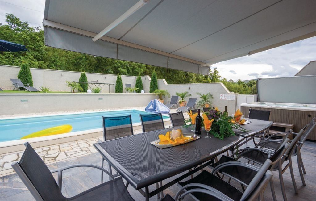 Terrass och pool bakom huset med utsikt över den intilliggande skogen.