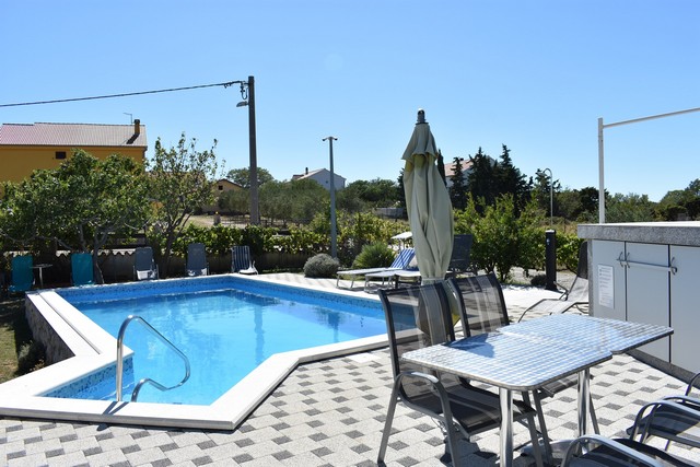 Utsikt från loungen över poolen och trädgården i Kroatien.