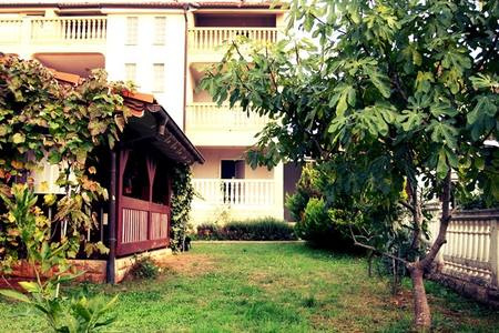 Husets trädgård med utsikt över husets baksida med balkongerna.