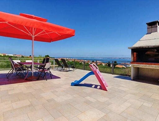 Terrass med grill och panoramautsikt över havet.