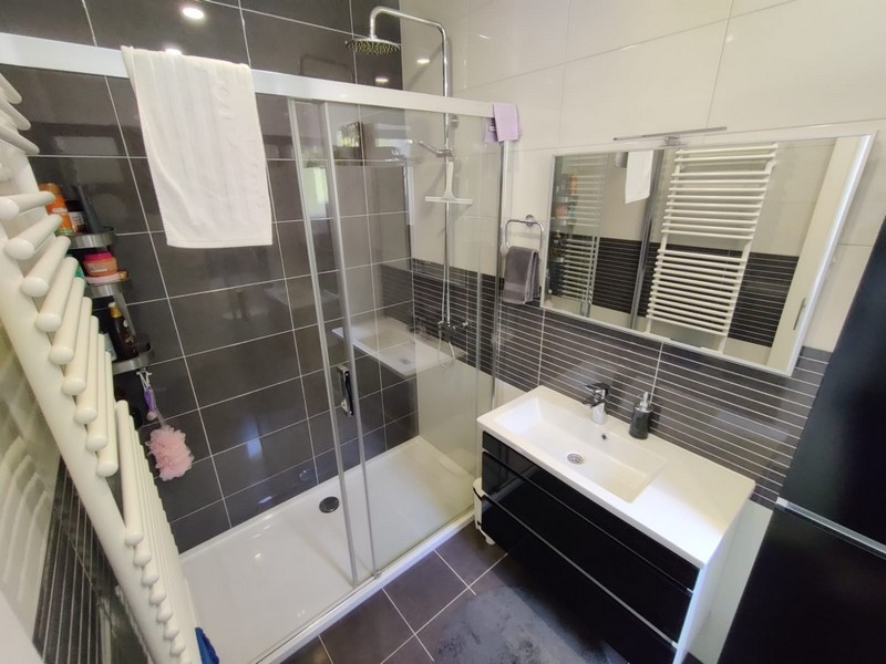 Badrum med brunt kakel och dusch.