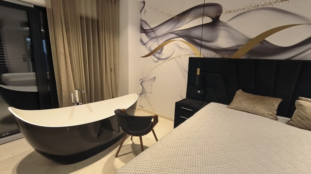 Sovrum med fristående badkar och stilren väggdesign