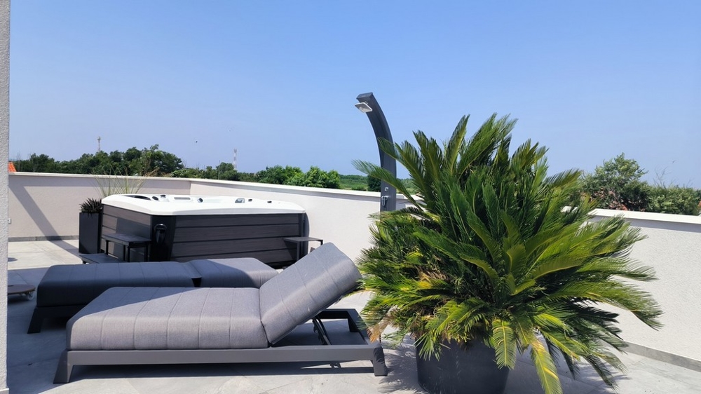 Takterrass med solstol, bubbelpool och utsikt över landskapet.