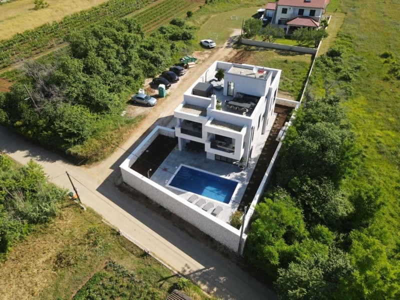 Flygfoto över modern villa med pool och takterrass