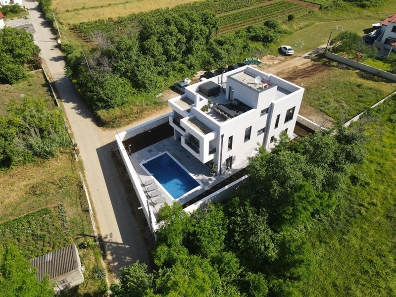 Flygfoto över en lyxig villa med pool i gröna omgivningar