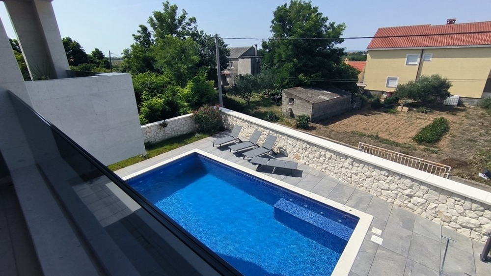 Poolområde med solstolar och naturstenvägg