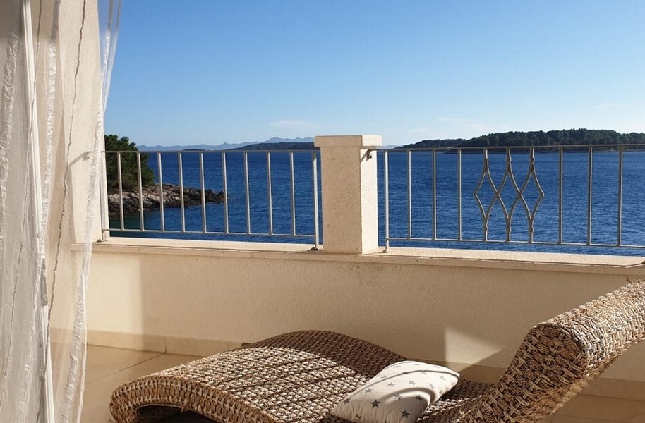 Terrass med havsutsikt och en avkopplande rottingstol.