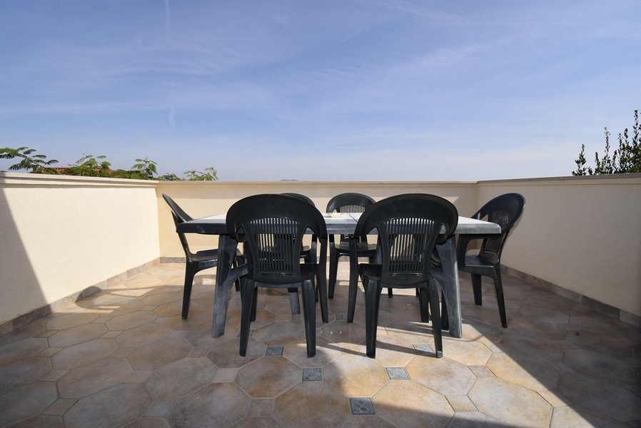 Rymlig, öppen terrass med enkla trädgårdsstolar.