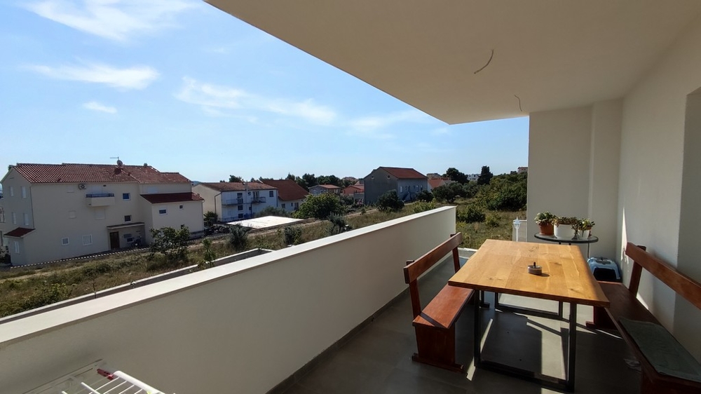 Rymlig balkong med matplats i ett familjehus i Vodice, Kroatien, med utsikt över de lugna omgivningarna.