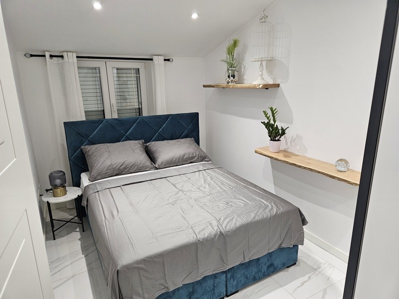 Mysigt sovrum med blå sänggavel och dekorativa växter i en fastighet i Kroatien