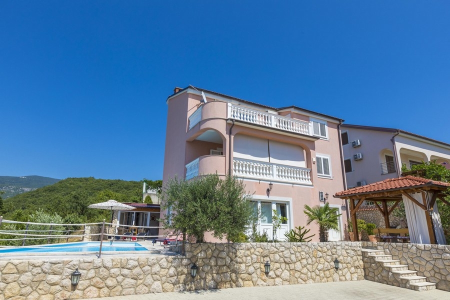 Dagtidsvy av ett rosa hyreshus i Kroatien med en pool