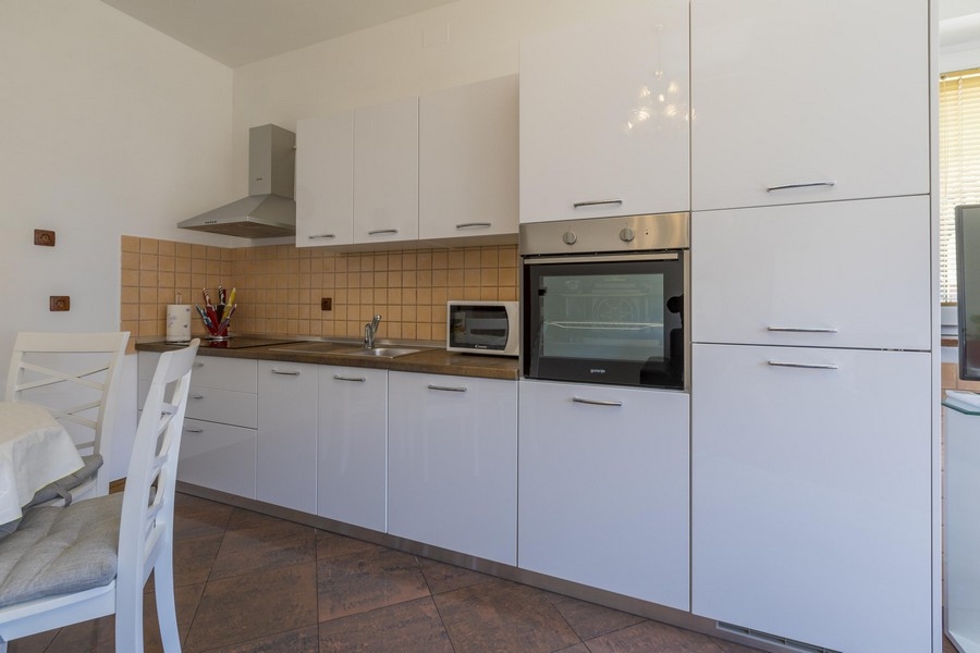 Modernt vitt kök med matplats i en strandfastighet i Kroatien