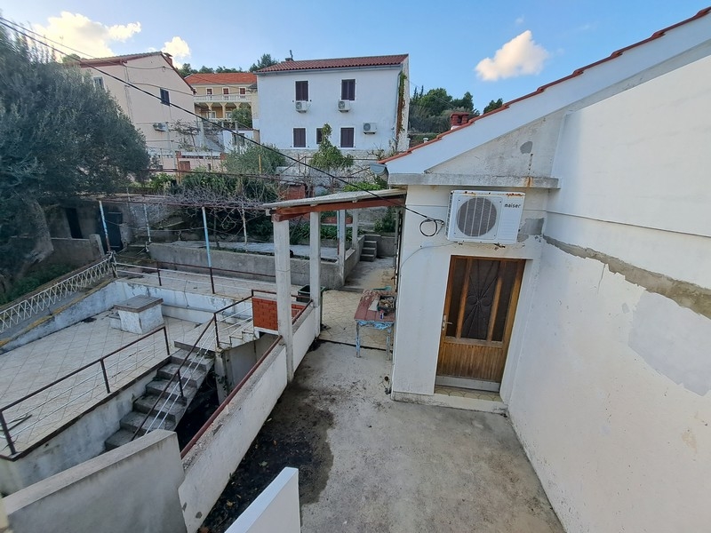 Bakgårdsområde på en kroatisk fastighet med täckt terrass och trappor, som erbjuds till försäljning av Panorama Scouting.