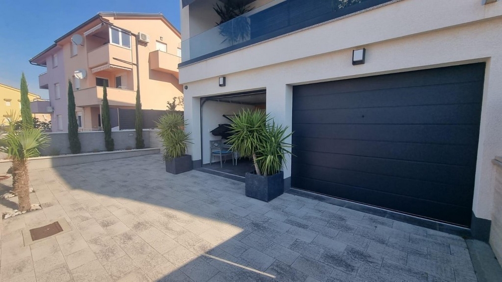 Främre trädgården på en modern kroatisk fastighet med garageportar