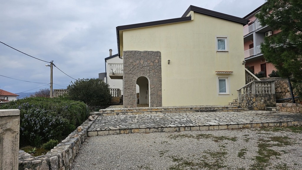 Baksidan av huset till salu i Karlobag med terrass och tillfartsväg