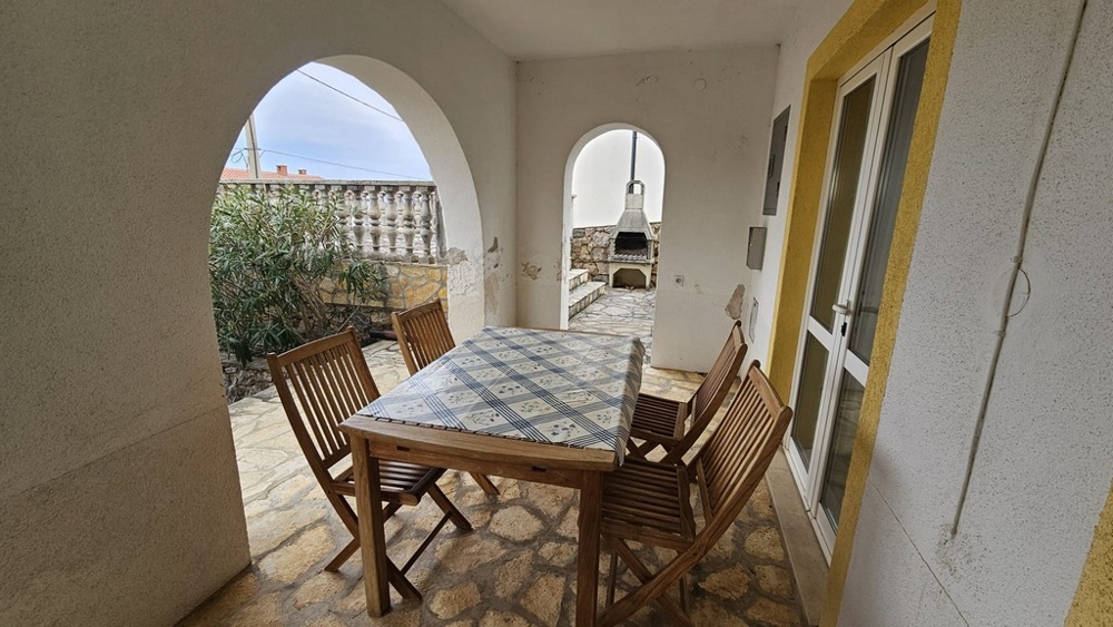 Övertäckt uteservering med matbord i hus till salu i Karlobag