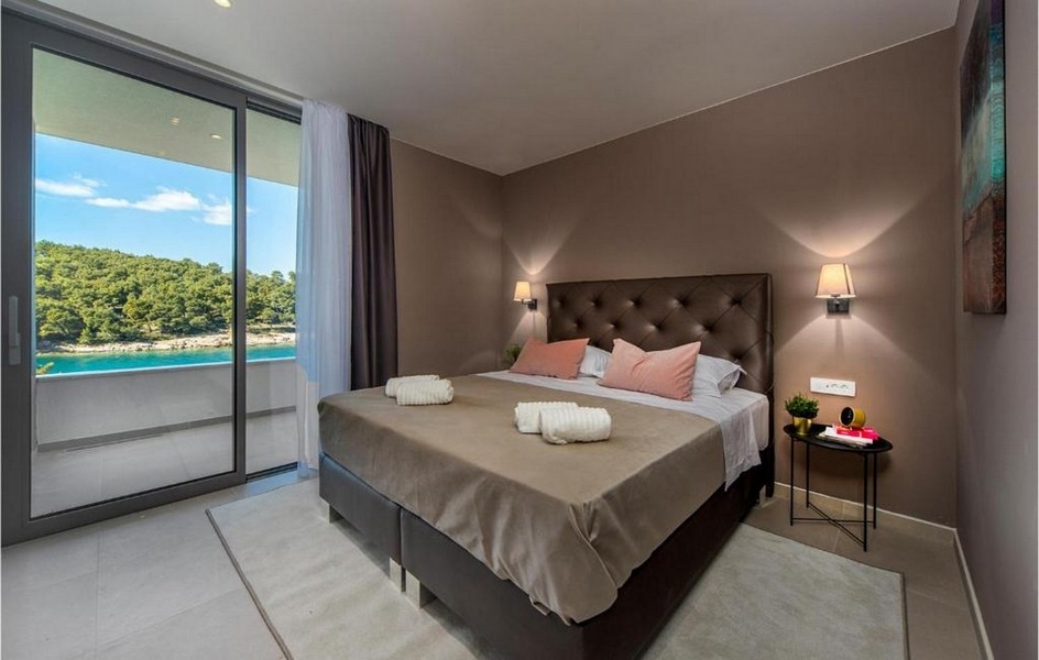 Sovrum med dubbelsäng, modern design och havsutsikt i villan på Brac.