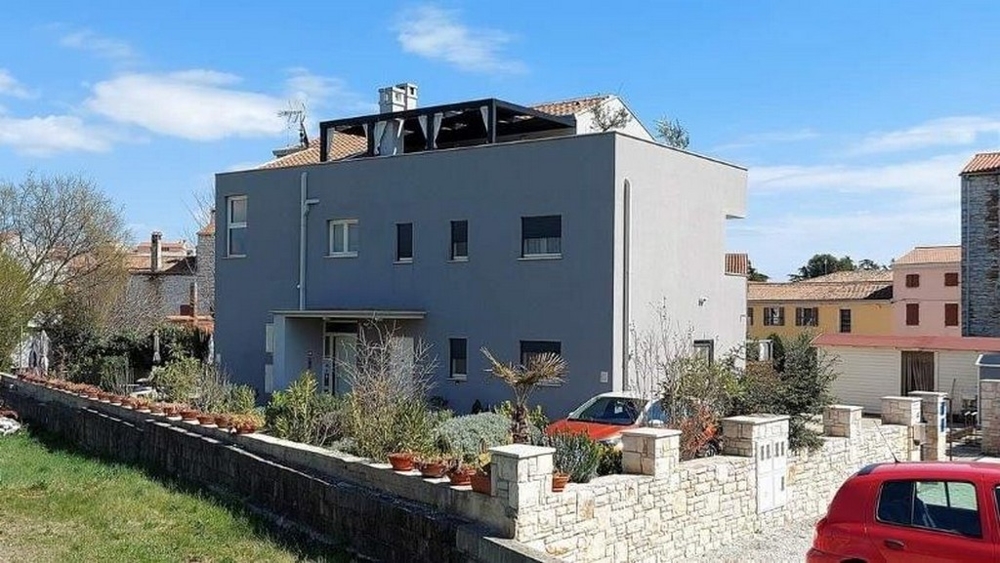 Sidovy av trelägenhetshus till salu i Istrien, med terrass och växtdekoration längs staketet.