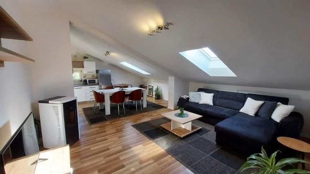 Mysigt vardagsrum på vinden i huset med tre lägenheter i Istrien, till salu, med soffa, matbord och öppet pentry.