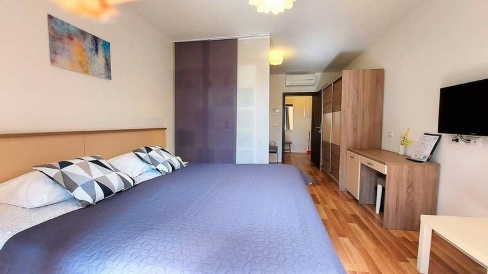 Sovrum i en av de tre lägenheterna i huset till salu i Istrien, med en stor säng, garderob och TV.