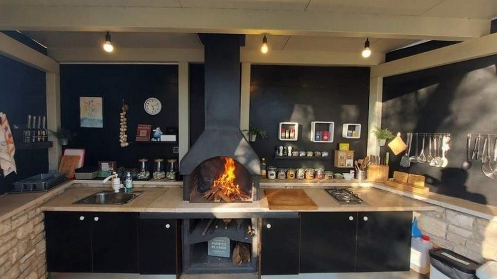 Kök med grill spis i hus med tre lägenheter i Istrien, till salu, med svarta arbetsytor och moderna köksmaskiner.