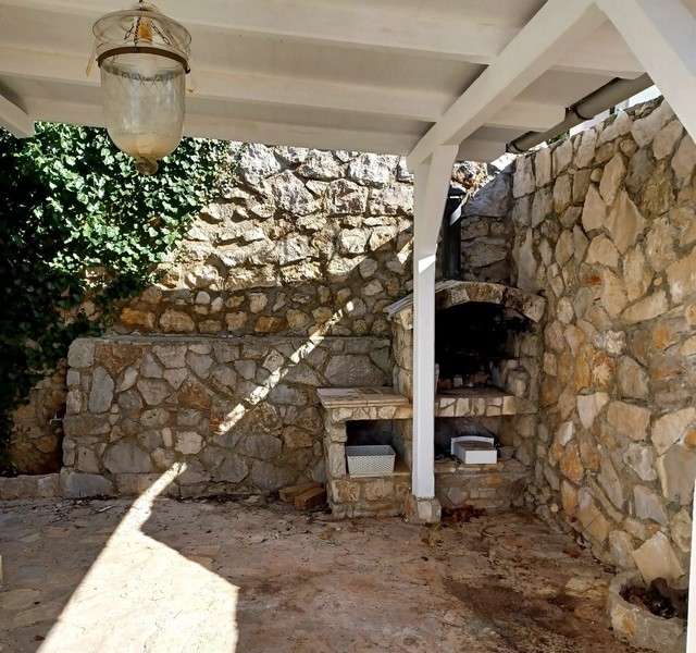 Utekök med traditionell stenugn i en villa till salu på ön Cres, Kroatien, under ett vitt tak