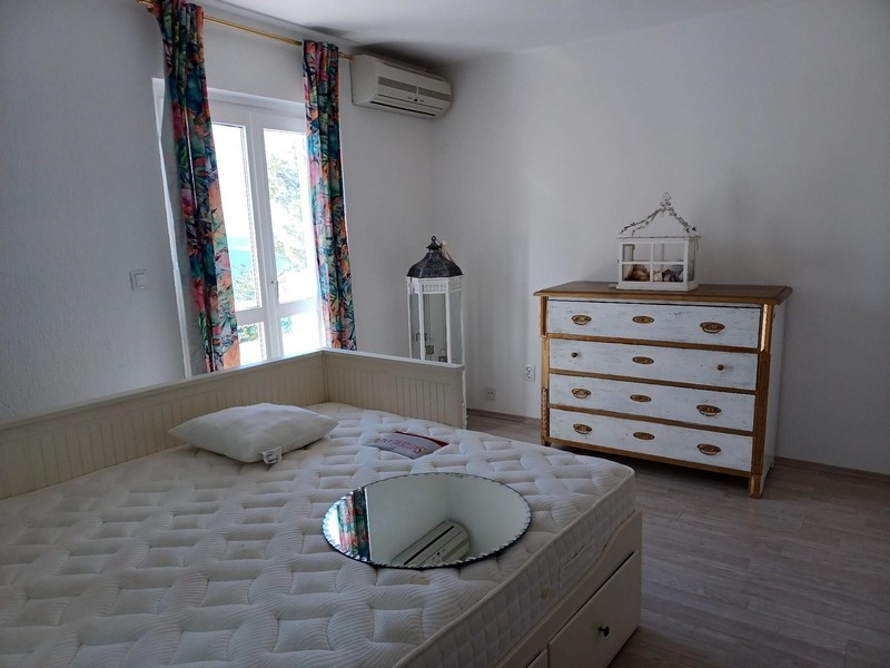 Sovrum med dubbelsäng och vit byrå i en villa till salu på ön Cres, Kroatien, med utsikt över naturen