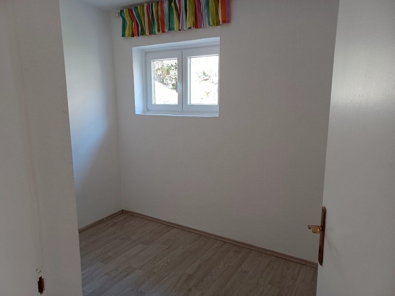 Enkelt, tomt rum med fönster och trägolv i en villa till salu på ön Cres i Kroatien