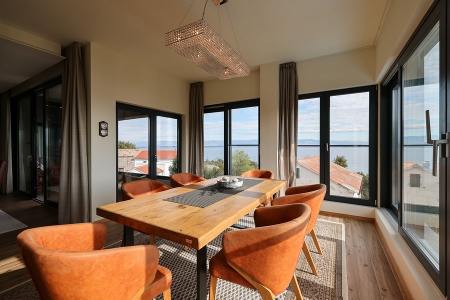Matplats med träbord, orange stolar och havsutsikt i villa till salu på Ugljan.