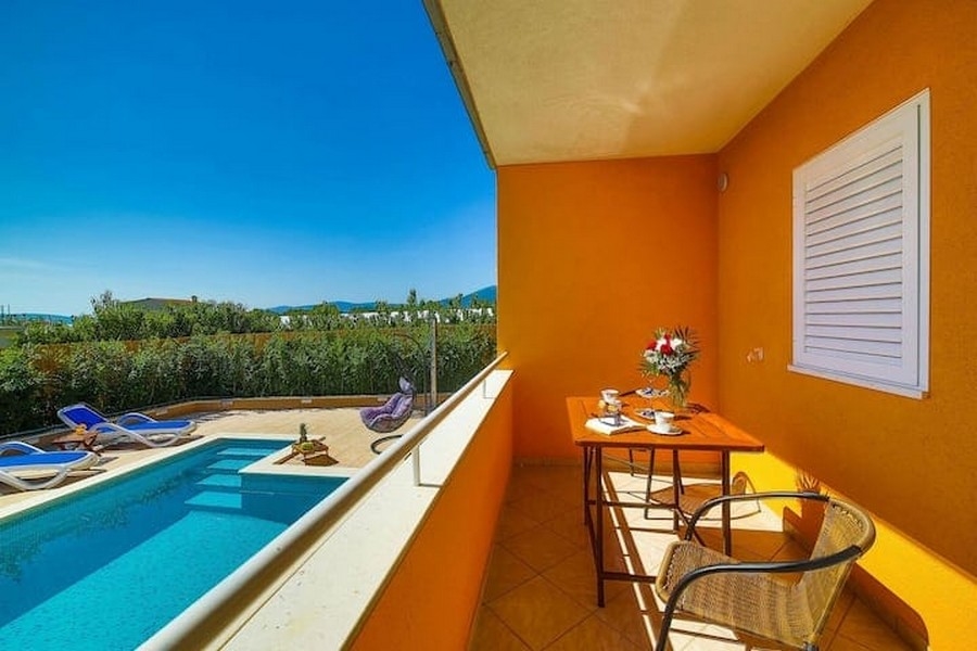 Balkongutsikt över poolområdet i hyreshuset i Kaštel Lukšić, Kroatien, med bord och stolar