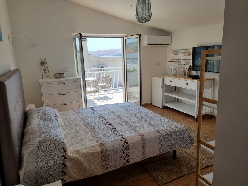 Ljus studiolägenhet med dubbelsäng, integrerat kök, balkongdörrar med havsutsikt, till salu i Karlobag, Kroatien, del av ett hyreshus precis vid havet.