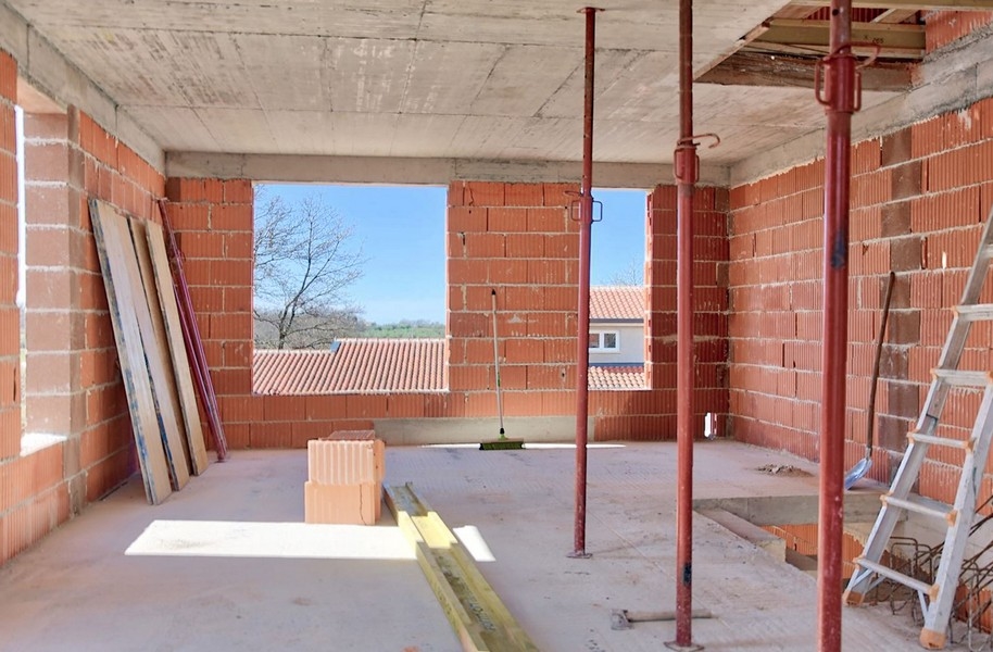 Interiörvy av parhuset under uppförande med utsikt utanför genom en stor öppning