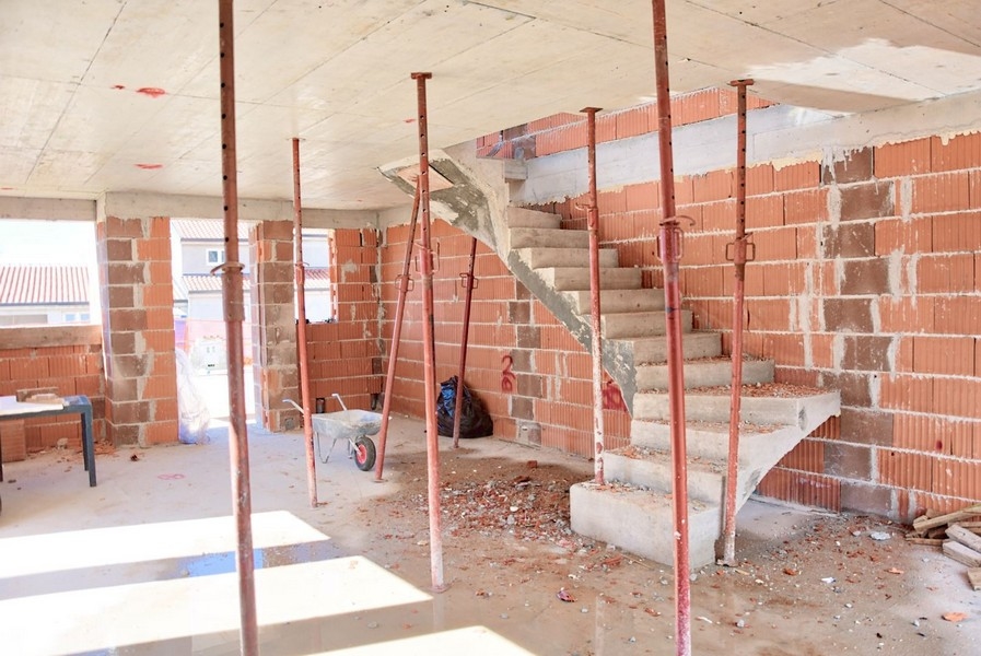 Interiörvy av parhuset under uppbyggnad med betongtrappor och tegelväggar